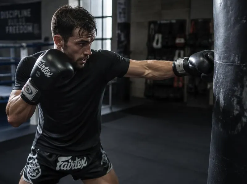 A man punching a heavy bag in the gym.